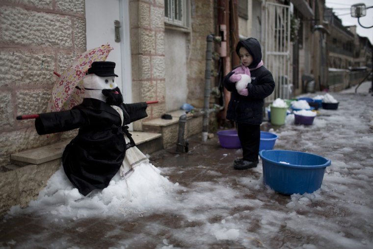 A young Ultra-Orthodox Jewish child plays next to a snowman in the Mea Shaarim neighborhood of Jerusalem on Dec. 12.