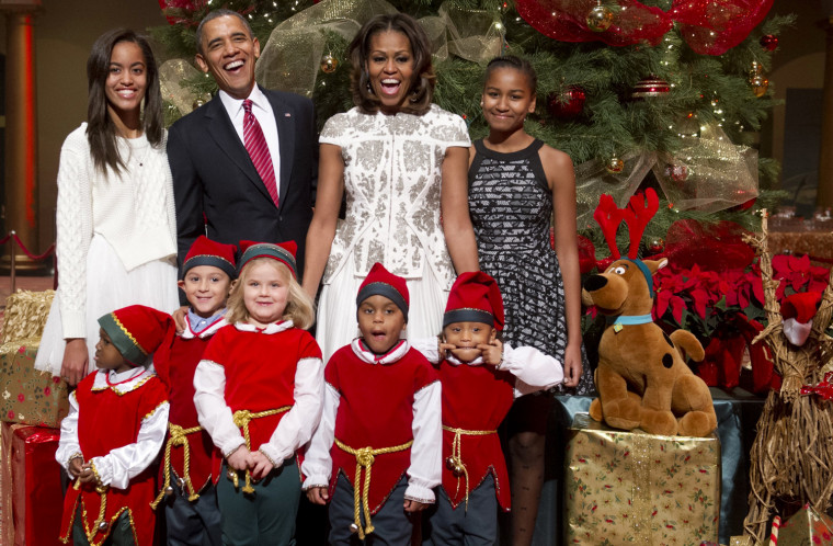 President Barack Obama, First Lady Michelle Obama and their daughters, Sasha and Malia, pose for photographs alongside children dressed as elves at the National Building Museum in Washington on Dec. 15, 2013.