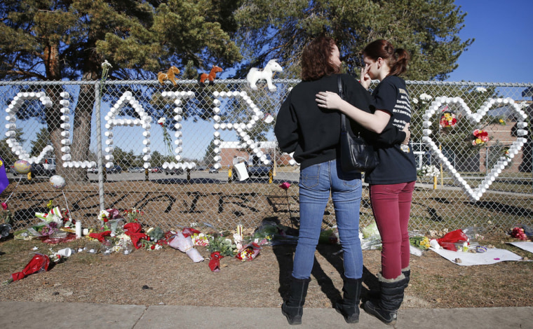 Arapahoe High School junior Emily Evans, right, and her mother Cristina hug while visiting a makeshift memorial bearing the name of wounded student Claire Davis, who was shot by a classmate during school three days earlier in an attack, in front of Arapahoe High School in Centennial, Colo., Monday, Dec. 16, 2013. Davis,17, was shot in the head at close range with a shotgun, and remains in a coma. (AP Photo/Brennan Linsley)