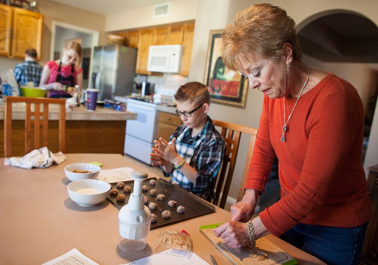 Leslie Davis helps her grandchildren bake holiday cookies on Saturday at her home in Mesa, Ariz.