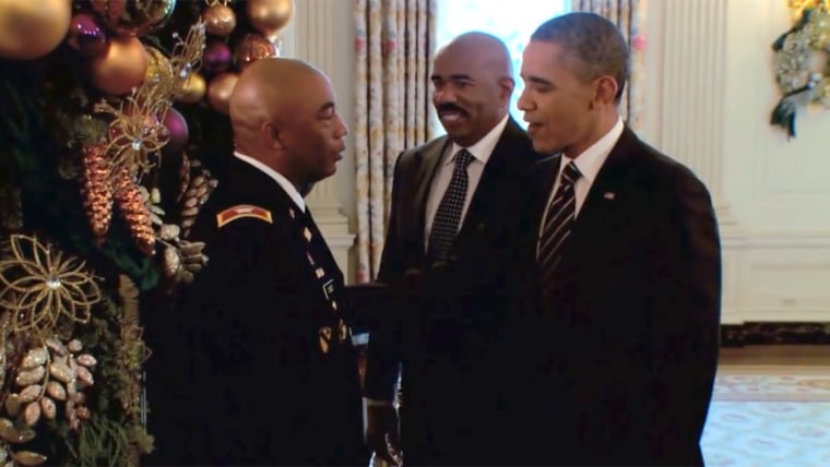 The president greets a member of the military as Steve Harvey looks on.