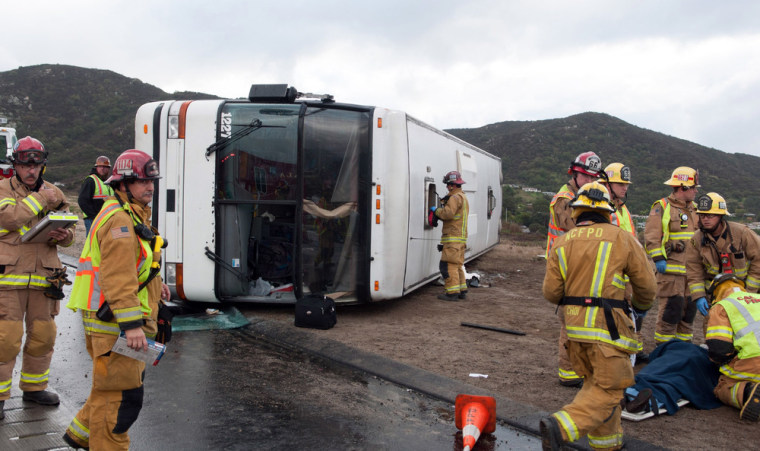 Firefighters tend to a victim, right, after a tour bus heading to a casino overturned on Interstate 15 near Fallbrook, Calif., in San Diego County Thursday afternoon, Dec. 19, 2013.