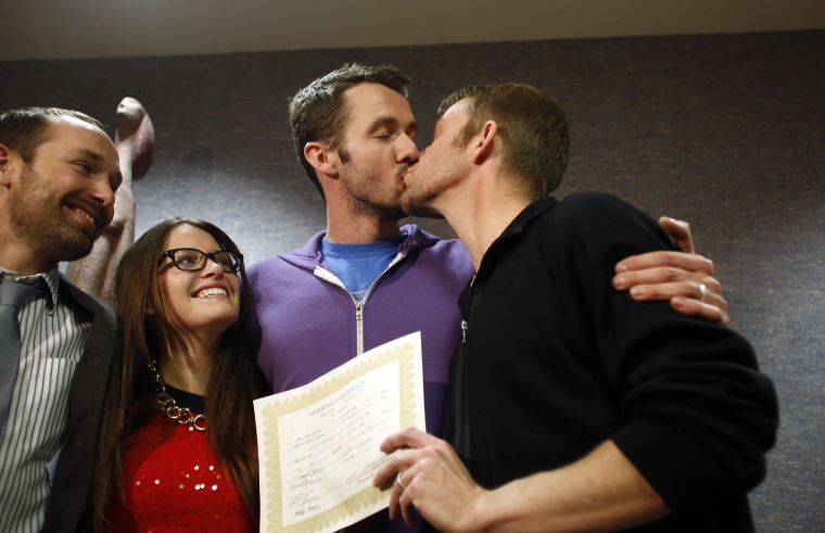 The first gay couple to be married in Utah, Michael Ferguson, second from right, and his husband, Seth Anderson, kiss as Blake Ferguson and his girlfriend Danielle Morgan watch after the pair married at the Salt Lake County Clerks office on Friday.
