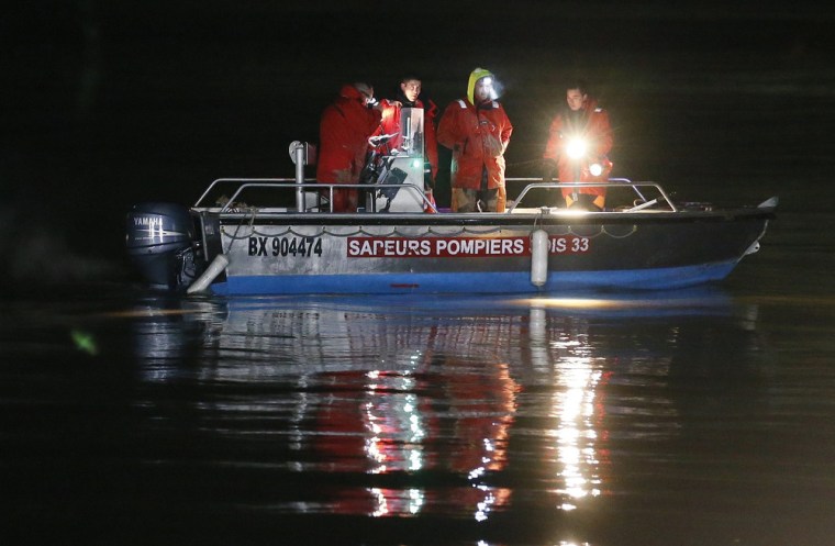 Rescue workers and divers look out from a boat during a rescue operation at the site of the helicopter crash.
