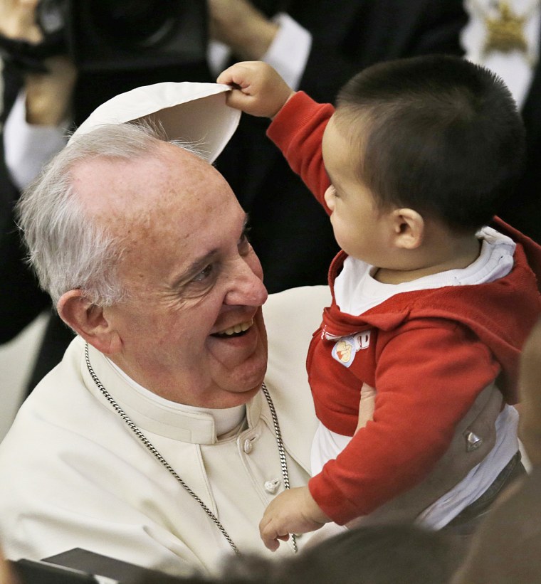 A child takes off Pope Francis' white zucchetto, or skullcap, during a meeting with children and volunteers of the Santa Marta Vatican Institute, at the Vatican, on Dec. 14, 2013.