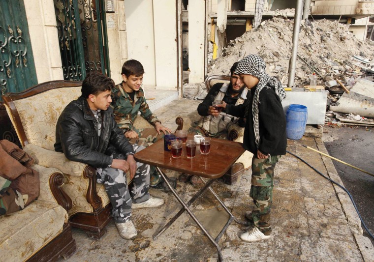 Hasan (right), an 11-year-old fighter in the Free Syrian Army, distributes tea to his fellow fighters at Aleppo's Karm al-Jabal district, on Dec. 7, 2013.