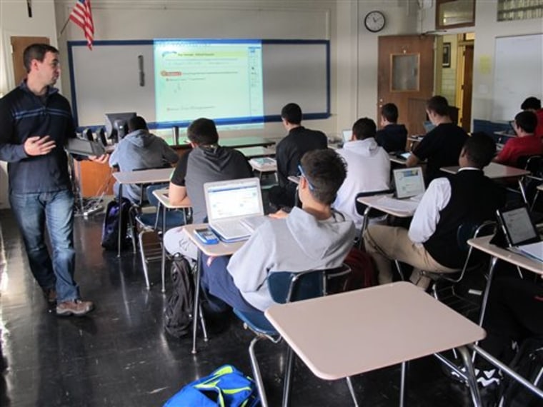 In this Dec. 13, 2013 photo, math teacher Richard Yapchanyk, left, leads a math class at Archbishop Stepinac High School as students use tablets and l...