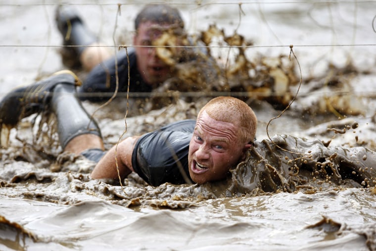 Competitors swim through mud underneath electrified wires during the Tough Mudder at Mt. Snow in West Dover, Vermont July 15, 2012. The Tough Mudder i...