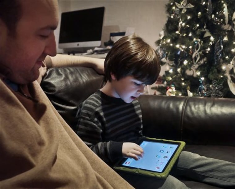 IMAGE: Adam Cohen watches as his son Marc, 5, uses a tablet