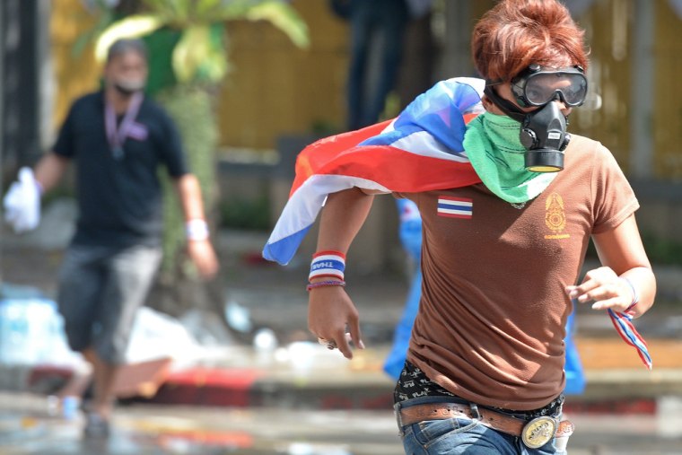 Thai anti-government protesters run from tear gas during a rally at a stadium to register party-list candidates in Bangkok on Thursday.