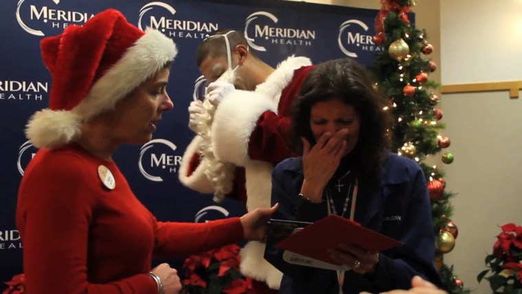 Leslie reacts to the letter as Travis, behind her, begins to shed his Santa suit.