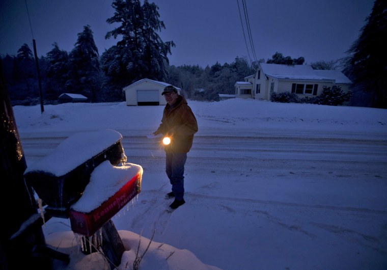 Jim Ridley uses a flashlight to get his mail Thursday in Litchfield, Maine, where he has been without electricity since Monday's ice storm.