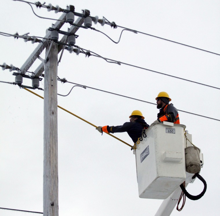 Eric Sheffer, left, and Matt Adams reconnect a power line Thursday in East Lansing, Mich.