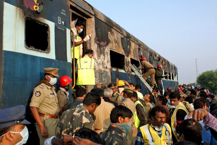 Rescue workers inspect the burned-out coach at the site of a train fire in Anantapur in the state of Andhra Pradesh, southern India, on Dec. 28, 2013.
