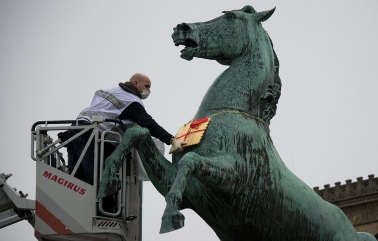 The missing golden Leibniz cookie hangs from the statue of a horse in front of the Leibniz University in Hannover, Germany, on Tuesday.