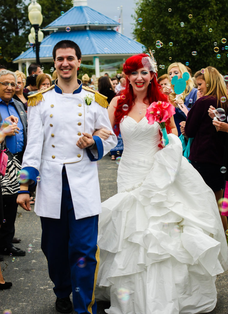 The bride and groom, now married, are greeted by guests blowing bubbles.