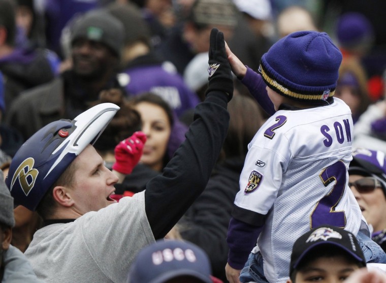 Two Ravens fans exchange high fives before a stadium victory rally in Baltimore.