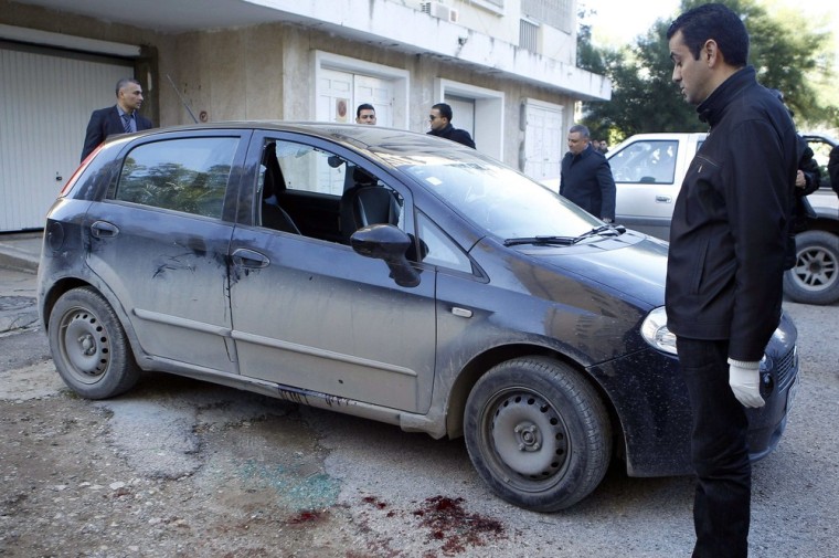 A forensic inspector looks at the car of opposition politician Chokri Belaid, who was shot dead outside his home in Tunis on Wednesday.