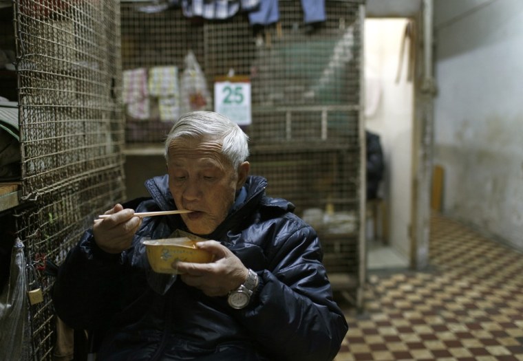 77-year-old Yeung Ying Biu eats next to his cage on Jan. 25, 2013. The cage homes date from the 1950s, when they catered mostly to single men coming in from mainland China