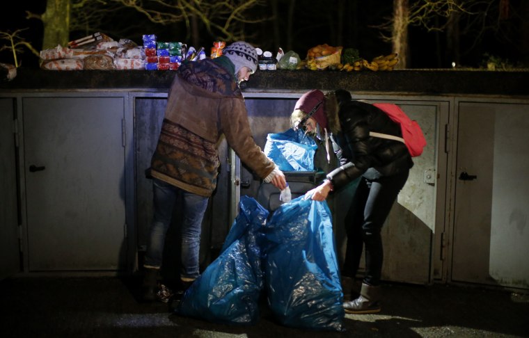 Benjamin Schmitt and Helena Jachmann, supporters of the foodsharing movement sort food found in a dumpster behind a supermarket in Berlin, Feb. 4.