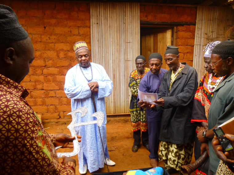 The Fon of Oku, leader of one of Cameroon's tribal groups, looks on as his aides examine a Cameroonian throwing knife that was purchased on eBay.