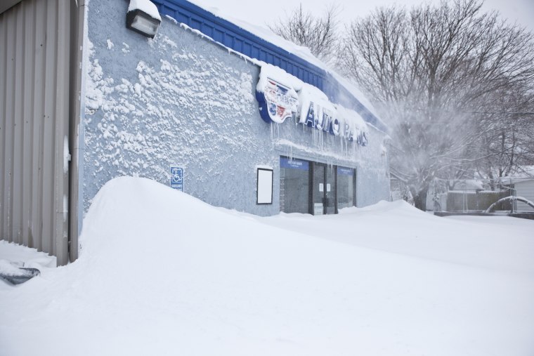 Snow partially covers the front of an auto parts store in Holbrook, N.Y.