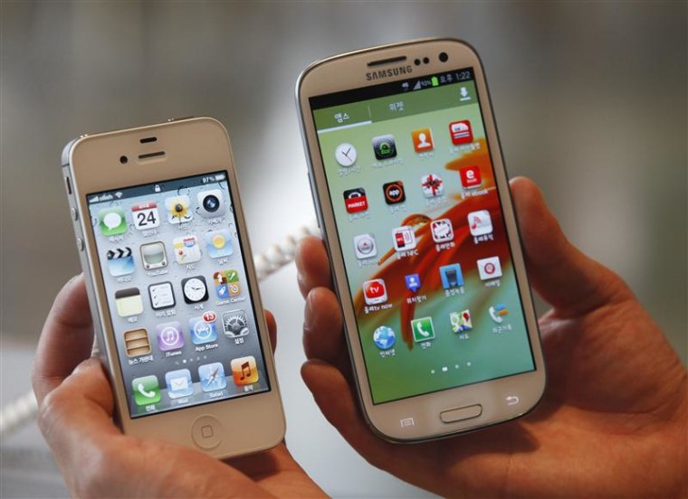 An employee holds Apple's iPhone 4s (L) and Samsung's Galaxy S III at a store in Seoul in this file photo from August 24, 2012. REUTERS/Lee Jae-Won/Fi...