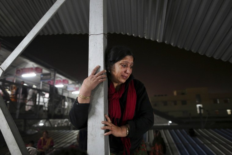 An Indian woman weeps as she watches from a staircase as rescue workers tend to the bodies of those killed in a stampede on a railway platform at the main railway station in Allahabad, India, Feb. 10,