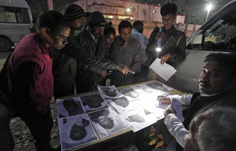 Relatives of the missing look at photos of victims of a stampede outside a hospital morgue in Allahabad on Feb. 11.