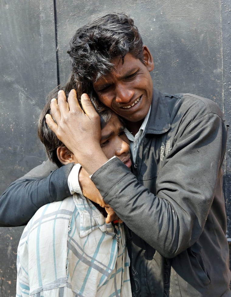 Two unidentified Indian men who reportedly lost their sister in a deadly stampede comfort each other outside a mortuary in Allahabad on Feb. 11.