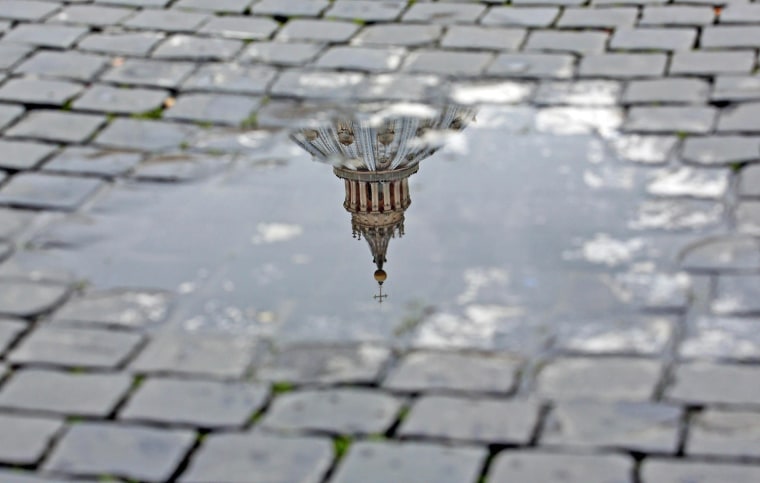 The cross on top of the St. Peter's dome is reflected in a puddle following Pope Benedict XVI's announcement of his abdication on Feb. 11.