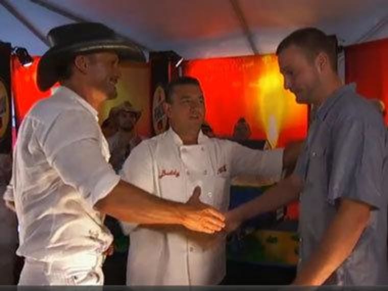 Tim McGraw and Buddy Valastro greet Marine Chris Chaput on \"Cake Boss.\"