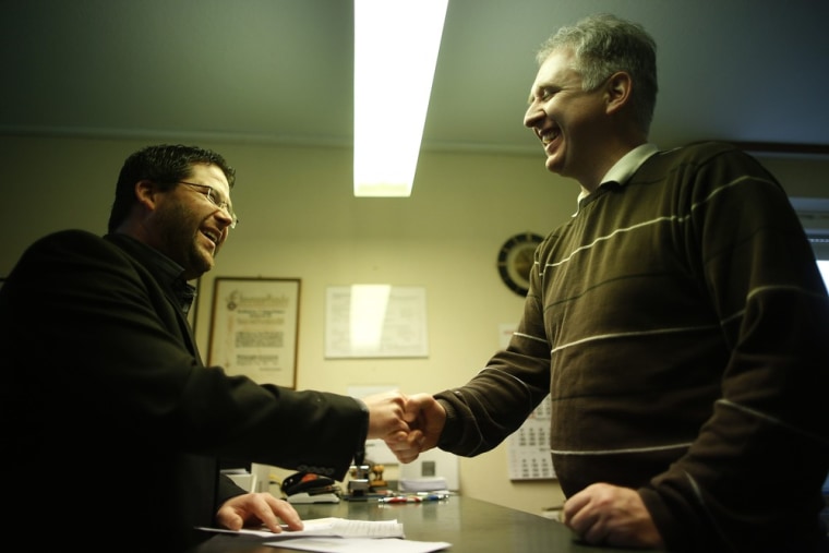 Peter Breiter, right, welcomes customer Mandes Rueger, 30, at the counter of the bank. Rueger, an insurance salesman, comes in around twice a week to use the bank.
