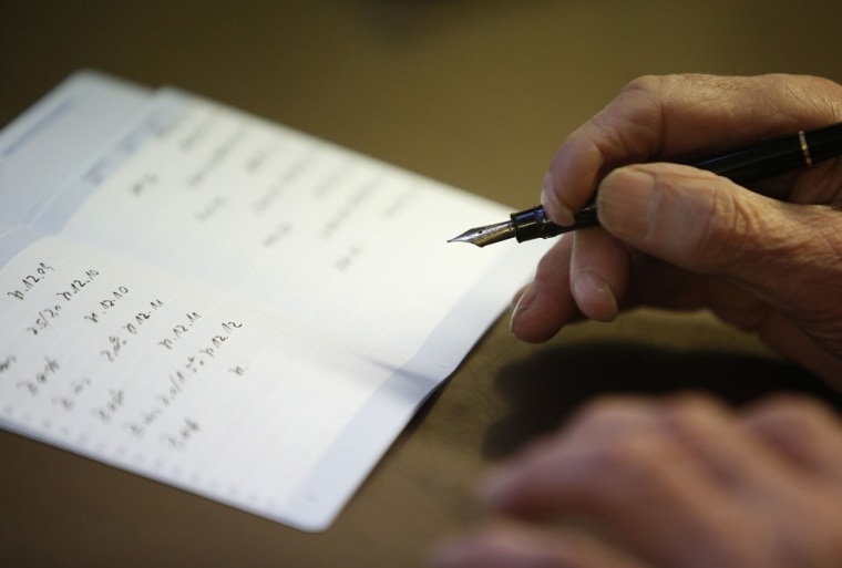 Fritz Vogt, 82, who used to run the bank and still helps out with paperwork, writes into a savings book. During his time at the bank he rejected the idea of IT, preferring his trusty fountain pen, and now eyes the 'new' computer with its floppy disks warily.