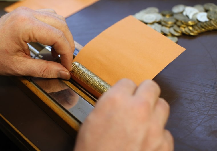 Peter Breiter rolls euro coins in paper.