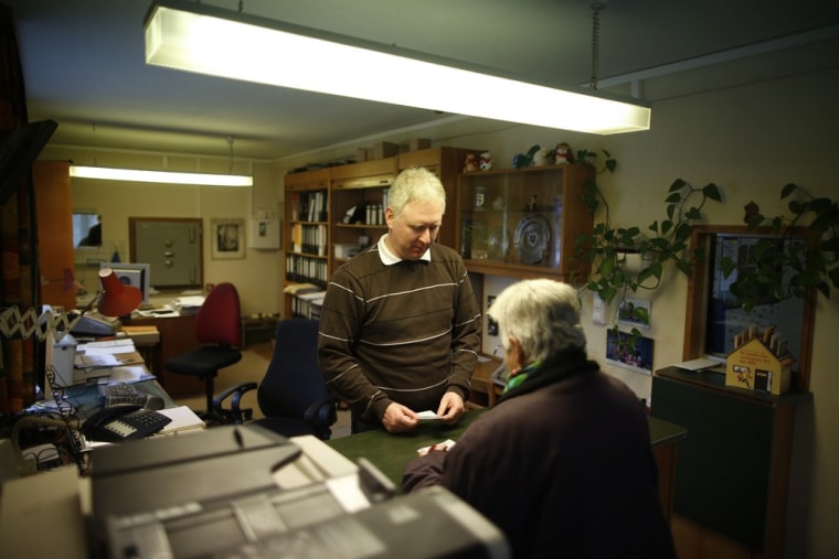 Peter Breiter, CEO of Raiffeisen Gammesfeld eG bank, serves a customer at the counter of the bank in Gammesfeld, Baden-Wuerttemberg.