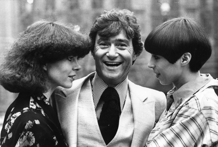 In this 1975 photo, Vidal Sassoon stands between two contrasting examples of his hairdressing at a teach-in at the Albert Hall, where he returned to hairdressing after a five-year break.