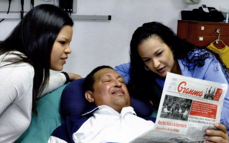 Venezuela's President Hugo Chavez holds Cuba's Gramma newspaper as his daughters, Rosa Virginia (right) and Maria look on.