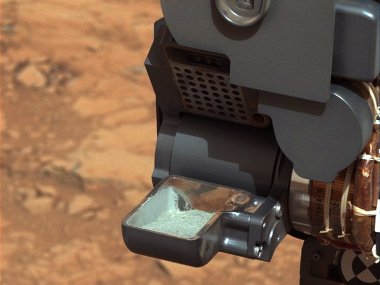 This image from NASA's Curiosity rover shows the first tablespoon of powdered rock extracted by the rover's drill. The image was taken after the sample was transferred from the drill to the rover's scoop.