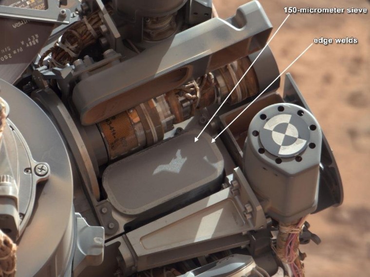This image from October 2012 shows the location of a sieve screen on the Curiosity rover that is used to remove large particles from samples before delivery to science instruments. Scientists say problems that came to light on a test unit on Earth have led them to change their procedures for sifting Martian samples.