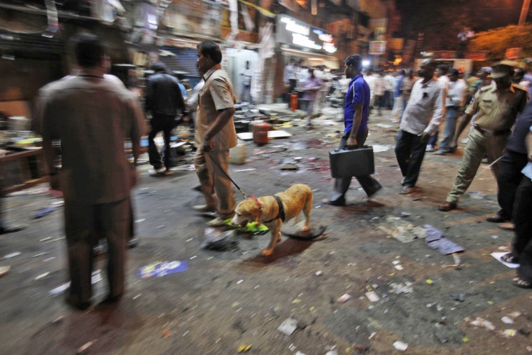 A member of the bomb squad with a sniffer dog arrives at the spot after a bomb blast in Hyderabad on Feb. 21.