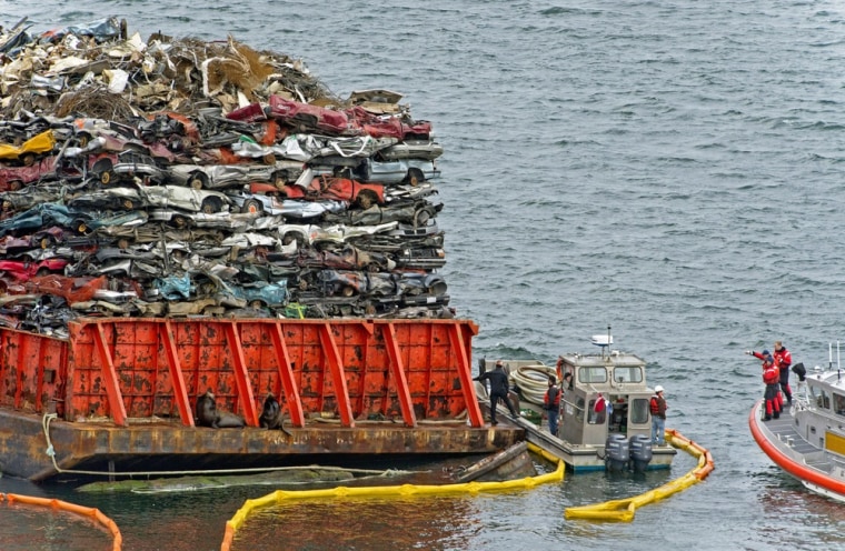 Emergency responders talk boat-to-boat next to the barge laden with scrap car hulks anchored near the northern shore of Commencement Bay, in Tacoma, Wash., Sunday, Feb. 24, 2013.