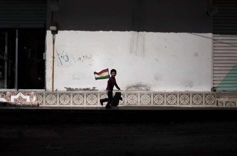 A boy runs as he holds a Kurdish flag in Ras al-Ayn, Syria, on Wednesday. The U.N. says more than 70,000 people have been killed since Syria's civil war started in March 2011.