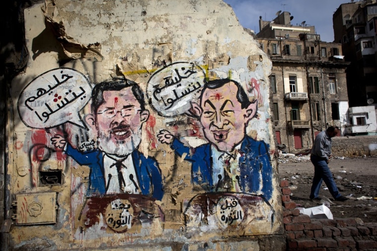 An mural depicts ousted president Hosni Mubarak, right, and Egyptian President Mohammed Morsi, left, with Arabic that reads