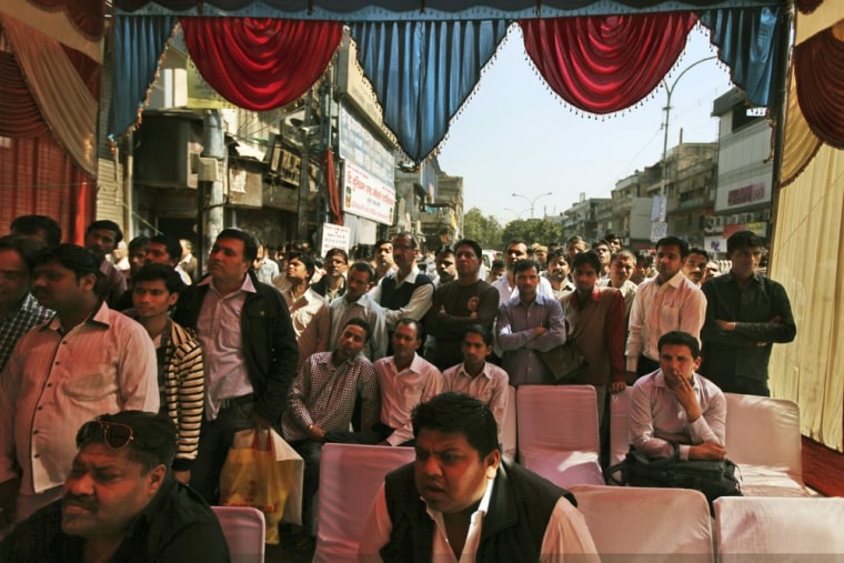 Traders and onlookers watch a live telecast of Indian Finance Minister Palaniappan Chidambaram presenting the annual budget on a television installed at a marketplace in New Delhi on Feb. 28, 2013. Chidambaram unveiled a national budget with a promise to put Asia's third largest economy back on a path of high growth and to check runaway inflation and the fiscal deficit.
