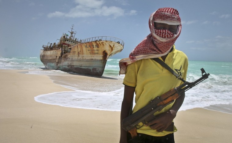 Masked pirate Hassan stands near a Taiwanese fishing vessel that washed up on shore near Hobyo, Somalia, after pirates were paid a ransom and released the crew in September 2012.