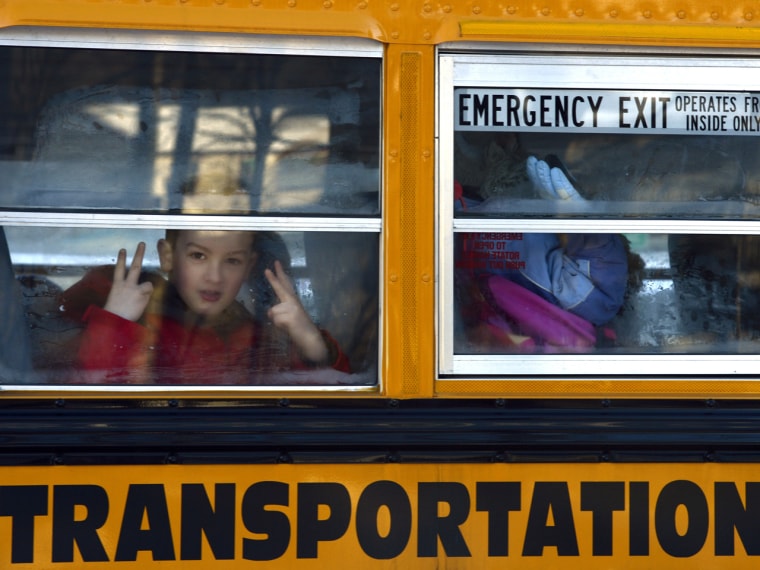 A Sandy Hook Elementry student flashes a sign as children leave on a school bus  in Newtown, Connecticut January 3, 2013. Counselors say getting back to a routine is the best medicine for the surviving students.