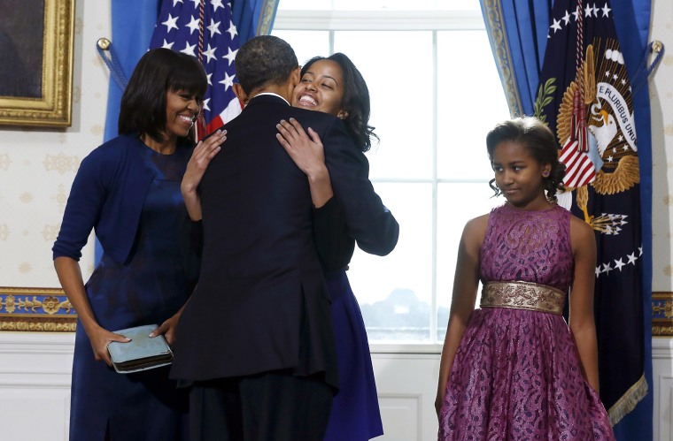 President Barack Obama gets a hug from his daughter Malia as wife Michelle, left, and daughter Sasha look on in the Blue Room of the White House in Washington, D.C., Jan. 20.