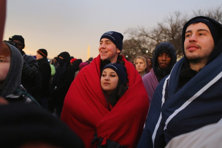 Brandon Adamski and Alicia Burke keep warm in a blanket as they and others gather near the U.S. Capitol building on the National Mall for the Inauguration ceremony on Jan. 21, in Washington, D.C.