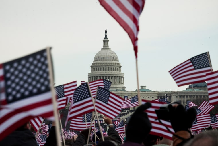 Flags fly as the crowd on the National Mall cheers during inauguration ceremonies on Jan. 21.